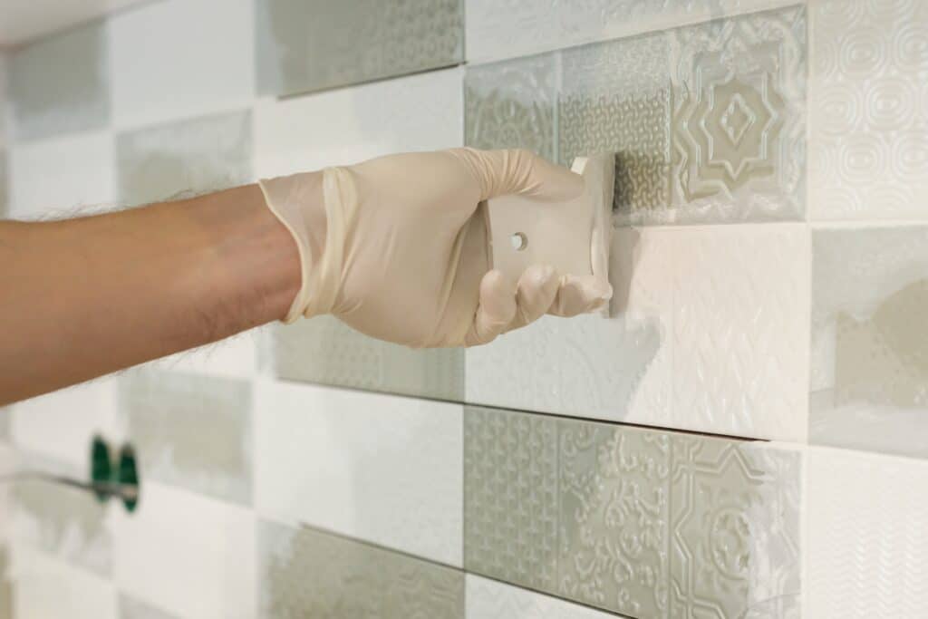 Closeup of tiler hand rubbing tile, Installing and grouting decorative finishes in environments with an high aesthetic value. Two-component, decorative, acid resistant epoxy grout.
Covering Tile with Epoxy 